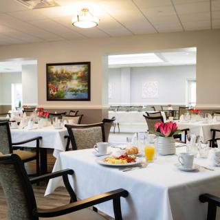 A well-arranged dining area with tables set for a meal, featuring white tablecloths and elegant decor.