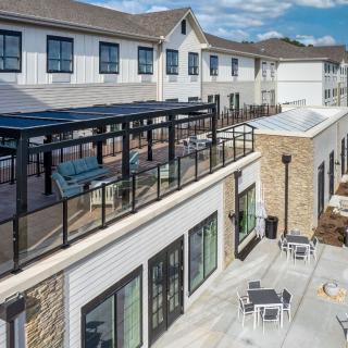 A modern commercial building with outdoor seating and a glass railing on the upper level.