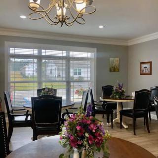 A well-lit dining room with elegant furniture and floral decorations.