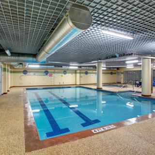 A spacious indoor swimming pool with clear blue water and a tiled floor, providing a relaxing environment for fitness and recreation.