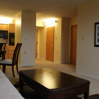 A cozy living room interior with a table and chairs, leading into a hallway.