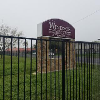 Entrance sign of Windsor facility surrounded by a fence on a cloudy day.