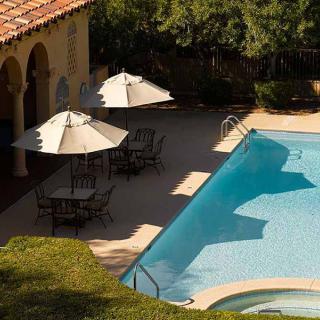 A serene outdoor swimming pool area with patio umbrellas and chairs on a sunny day.