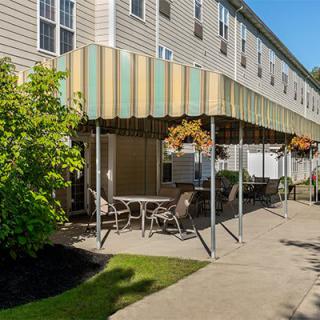 Outdoor patio area with seating and awning attached to a building.