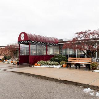 A bus stop with a glass shelter and bench on an overcast day.