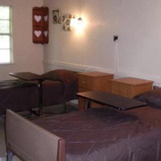 A modestly furnished bedroom with two beds and wooden furniture.