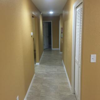 A well-lit hallway with doors on either side and tiled flooring.