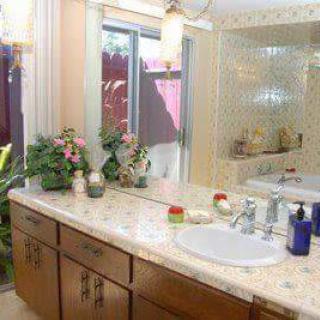 A well-decorated bathroom featuring a large mirror, plants, and a tidy countertop with a sink.