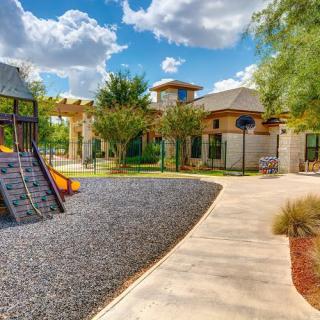 A sunny day at a children's playground with a nearby building and pathway.