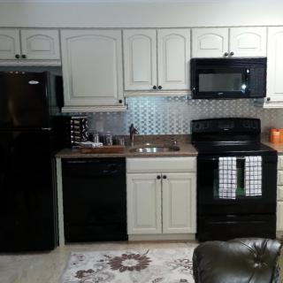 Modern kitchen with black appliances and white cabinets.