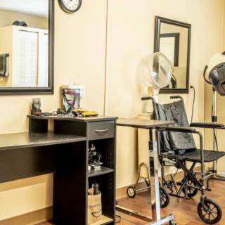 A salon setup featuring a hair dryer, desk, and mirrors.