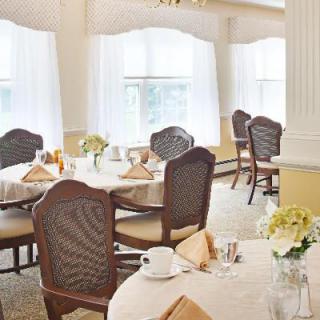 An elegant dining room with neatly set tables and ample natural light.