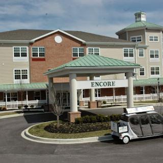 A senior living facility with modern architecture, featuring a transportation vehicle at the entrance.