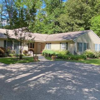 A suburban house with a spacious driveway and surrounding greenery on a sunny day.