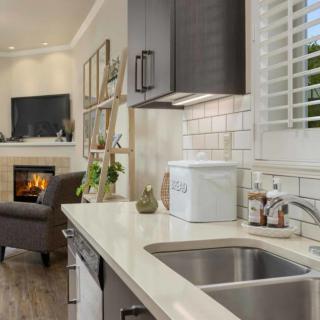 A modern open-plan kitchen and living room with a sleek countertop, sink, and cozy fireplace.