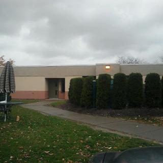 A quiet building surrounded by greenery on a cloudy day.