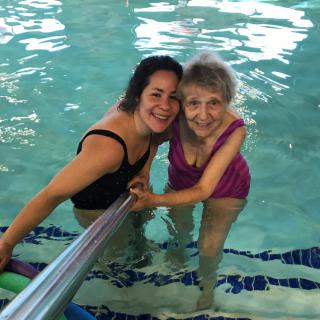 An elderly woman and a younger woman enjoying time together in a swimming pool.