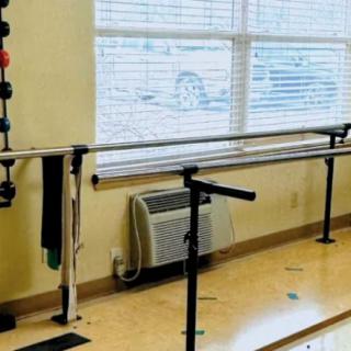 A physical therapy room with parallel bars for rehabilitation exercises.