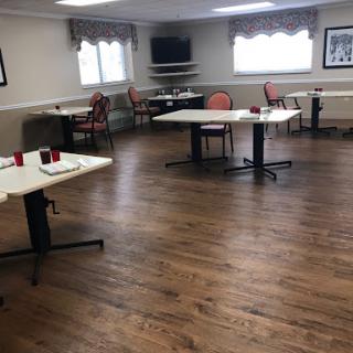 A spacious and well-lit room featuring several tables and chairs, designed for group activities or gatherings.
