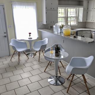 A modern kitchen and dining area with white furniture and a bright atmosphere.