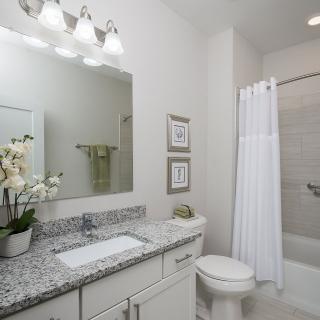 A modern bathroom with a granite countertop, large mirror, and minimalist decor.