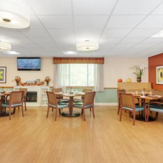 A cozy dining area with tables and chairs, featuring a television and decorative elements.
