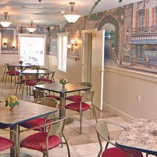 A cozy dining area featuring elegant tables and red chairs, complemented by a cityscape mural.