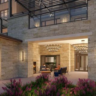 A modern building entrance featuring stylish lighting and outdoor seating amidst landscaped greenery.