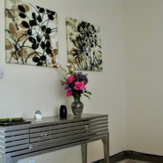 A chic interior space featuring a metallic console table adorned with a floral arrangement in a vase, complemented by abstract artwork on the wall.