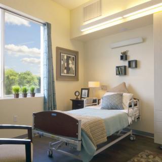 A well-lit hospital room with a single bed and a window view.