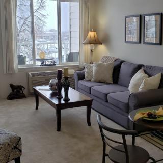 A cozy living room with a sofa, coffee table, and a large window letting in natural light.