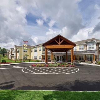 A modern building with a welcoming entrance and landscaped surroundings under a cloudy sky.