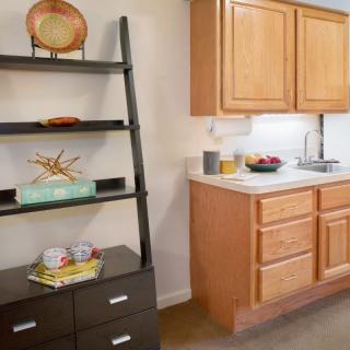 A cozy kitchen corner featuring a modern shelf and wooden cabinets.