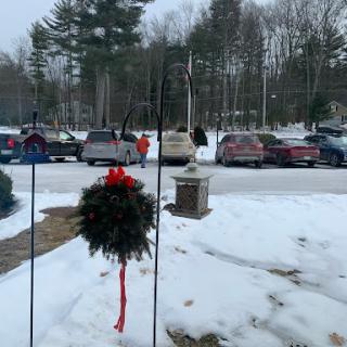 A snowy winter scene featuring a holiday wreath and parked cars.