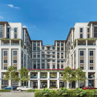 A modern multi-story building with a symmetrical facade and greenery, set against a clear blue sky.