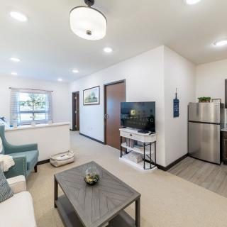 A modern, open-plan living room and kitchen area with bright lighting and contemporary furnishings.