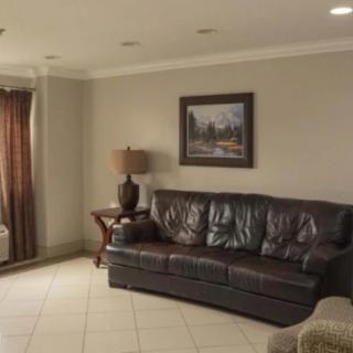 A cozy living room with a dark leather sofa, a side table lamp, and wall art.