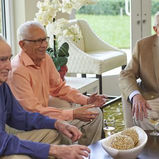A group of elderly men enjoying a conversation in a comfortable indoor setting.