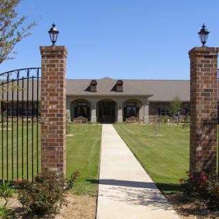 A welcoming entrance with a pathway leading to a modern building surrounded by greenery.