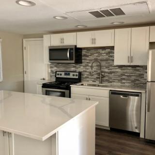 A modern kitchen with white cabinets, stainless steel appliances, and a kitchen island.