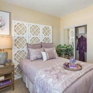 A cozy bedroom with a stylish headboard, decorative pillows, and a neatly arranged bedside table.