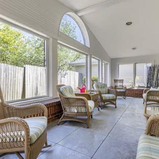 A bright sunroom with wicker furniture and large windows allowing natural light.