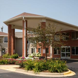 A brick building with a covered entrance and landscaped surroundings.