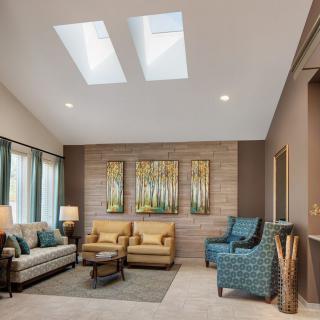 A modern living room featuring skylights, comfortable seating, and tasteful wall art.