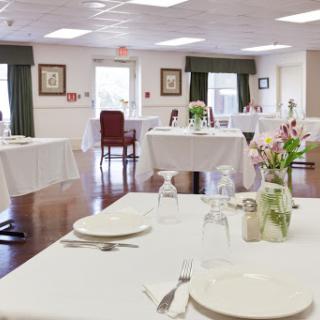 A beautifully set dining area featuring neatly arranged tables with white tablecloths and floral centerpieces, creating an inviting atmosphere.