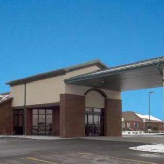 A commercial building with a covered entrance and adjacent parking lot.