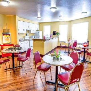 A bright and inviting cafe with red chairs, small tables, and a kitchen area.