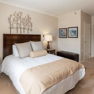A cozy bedroom with a neatly made bed, decorative pillows, and soft lighting.