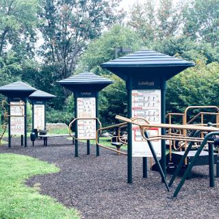 A well-designed outdoor fitness area featuring multiple exercise stations amidst a lush green setting.