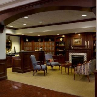 A classic and cozy lobby area with armchairs, a fireplace, and wood paneling.